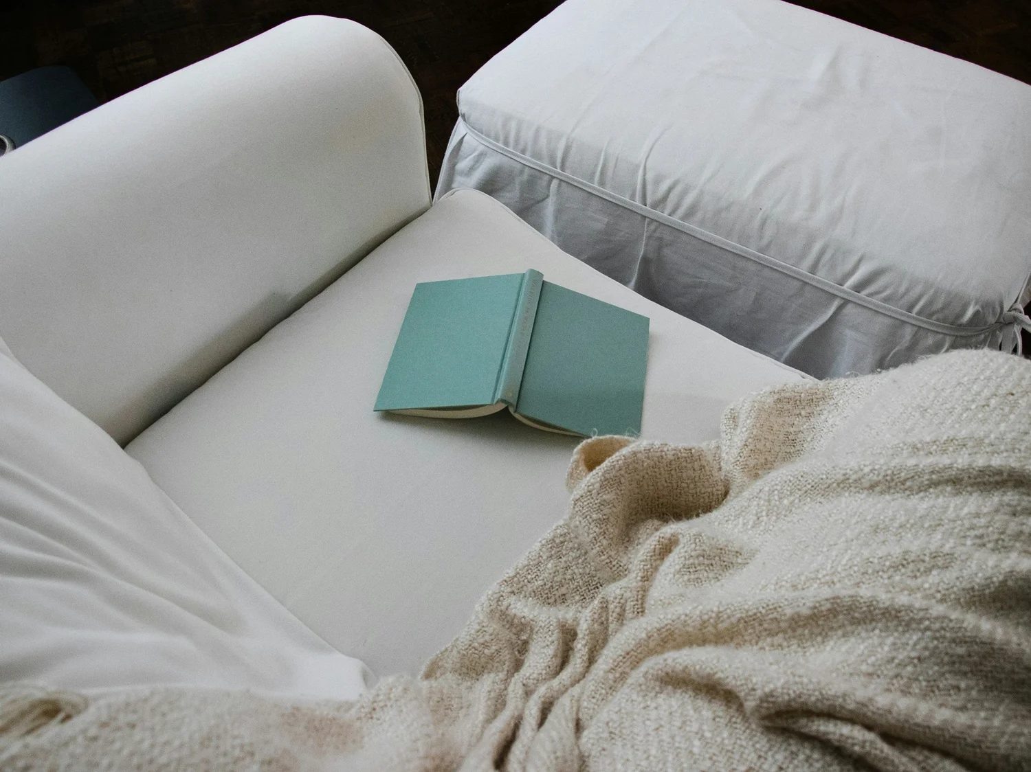 Open book and blanket beside a cup of tea